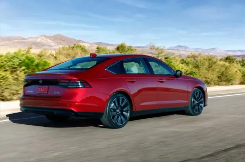 Red Honda Accord sedan driving on a desert highway with mountains in the background
