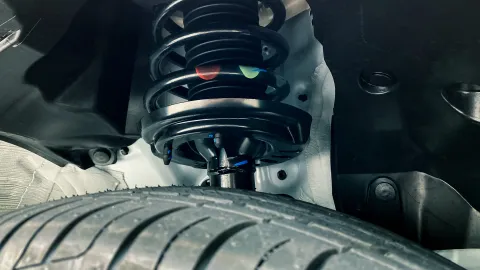 Vehicle suspension strut and coil spring assembly installed above the tire.