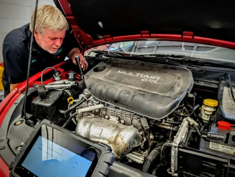 Gemba Automotive technician performing diagnostic testing under the hood of a vehicle.